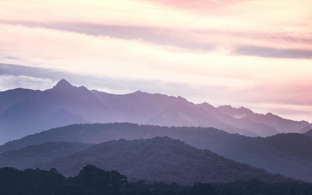 A wide-angle view of layered blue mountains at dawn, representing the expansive horizon of human imagination when balanced with AI writing efficiency.