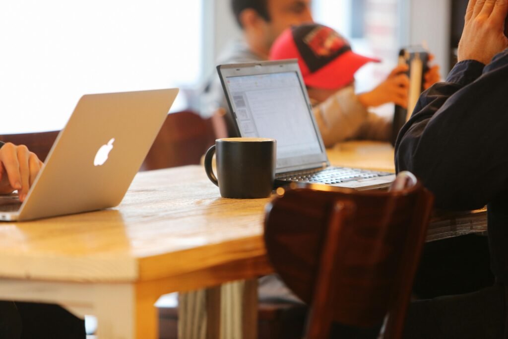 Writers using laptops at a casual workspace table, illustrating an academic editing showdown between Paperpal and ChatGPT.