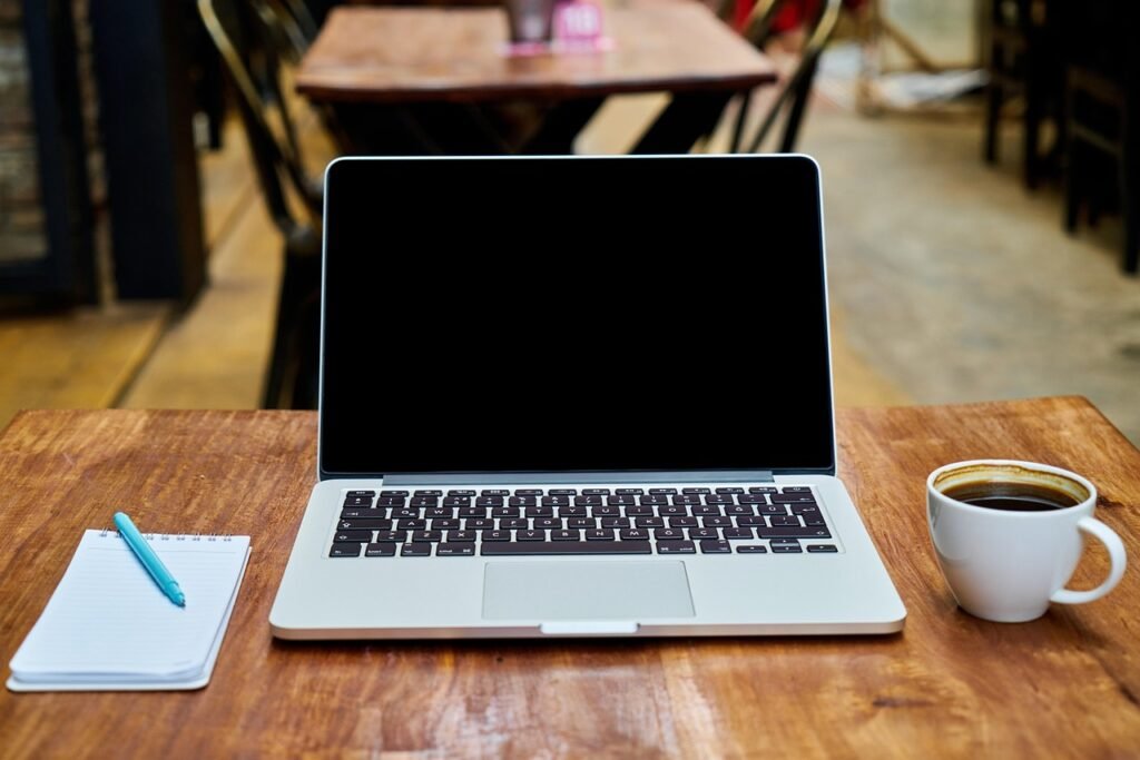 Laptop on a cafe table with a notebook and coffee, showing a modern AI writing workflow with Grammarly alternatives.