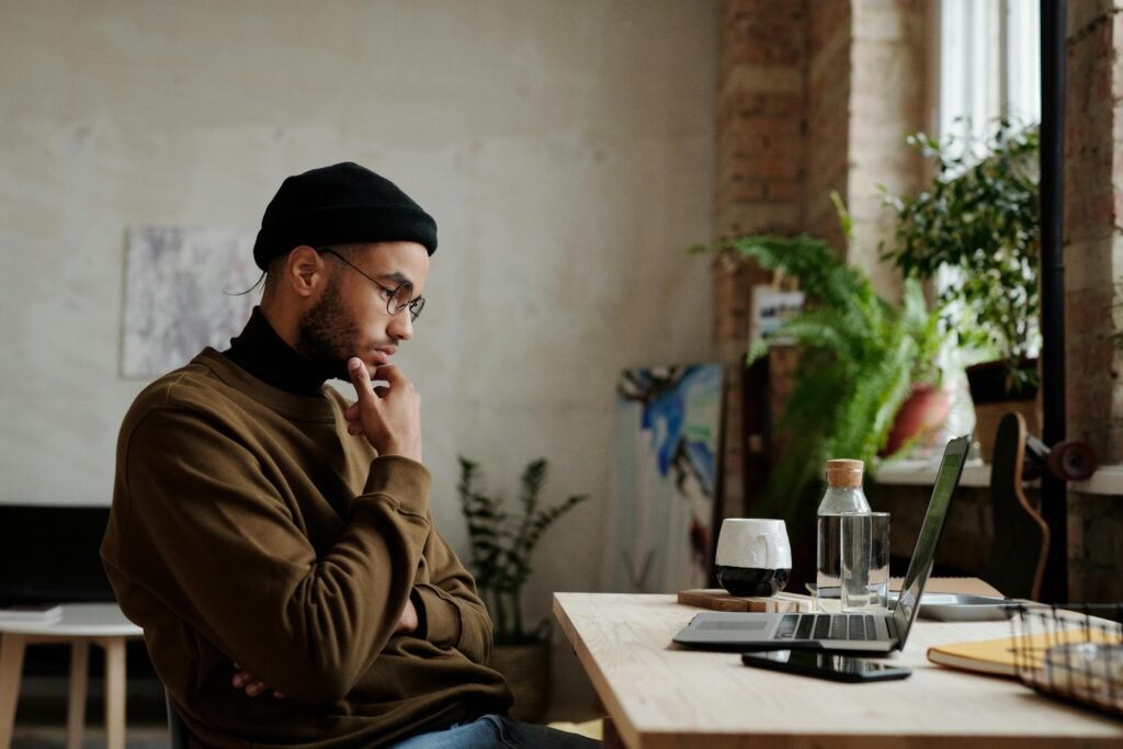 Researcher in a beanie looking thoughtfully at a laptop, representing deep academic analysis beyond simple grammar checks.