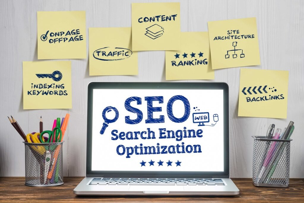 Laptop displaying SEO (Search Engine Optimization) text surrounded by sticky notes showing key SEO concepts including content, ranking, traffic, backlinks, and keywords.