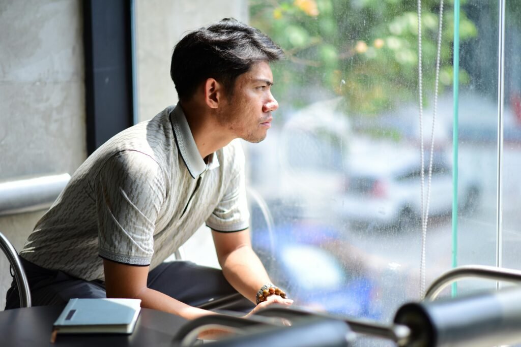 Student gazing thoughtfully out of window reflecting on AI use in academic writing.