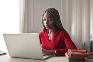 Researcher working on laptop with books nearby representing the balance between AI tools and human thinking in academic research.