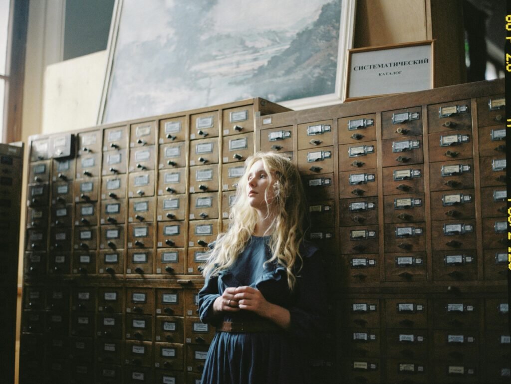 Student standing alone in front of old card catalogue looking uncertain representing the question of whether AI makes academic writing meaningless.