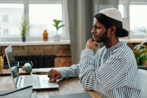 Researcher thoughtfully evaluating AI writing tools on laptop deciding between Jenni AI and ChatGPT.