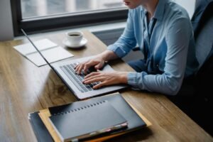 Content creator working on laptop with notebook and coffee comparing NeuronWriter and Frase SEO tools.